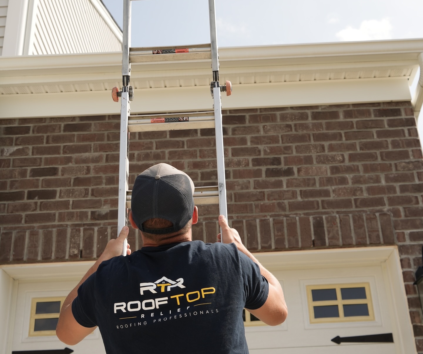 Rooftop Relief crew member setting an extension ladder against a brick Cincinnati home
